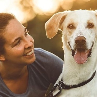 A woman smiling with a dog.